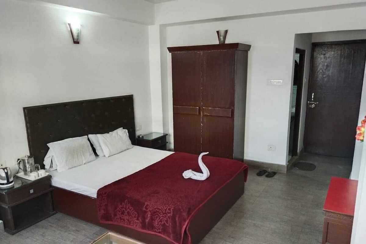 A hotel room with a bed, a wardrobe, a nightstand, and a red chair.