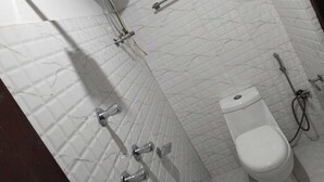 A bathroom with a toilet, a shower, and a towel rack. - BASSU'SHOTEL Silk Route Residency (Gangtok)