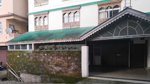 A building with a green roof, a stone wall, and a covered entrance. - BASSU'SHOTEL Silk Route Residency (Gangtok)