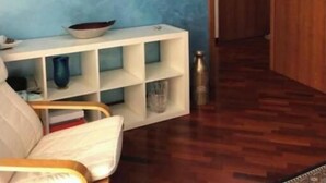 A room with a blue wall, a white console table, a framed painting, and a wooden door. - SPACIOUS 90 SQM APARTMENT WITH BALCONIES, PRIVATE PARKING - RAFFAELE DE FERRARI (Roma)