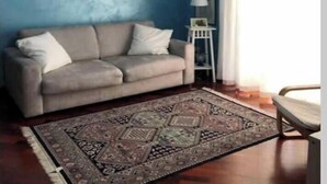 A living room with a blue wall, a beige sofa, a patterned rug, a chandelier, and a white chair. - SPACIOUS 90 SQM APARTMENT WITH BALCONIES, PRIVATE PARKING - RAFFAELE DE FERRARI (Roma)