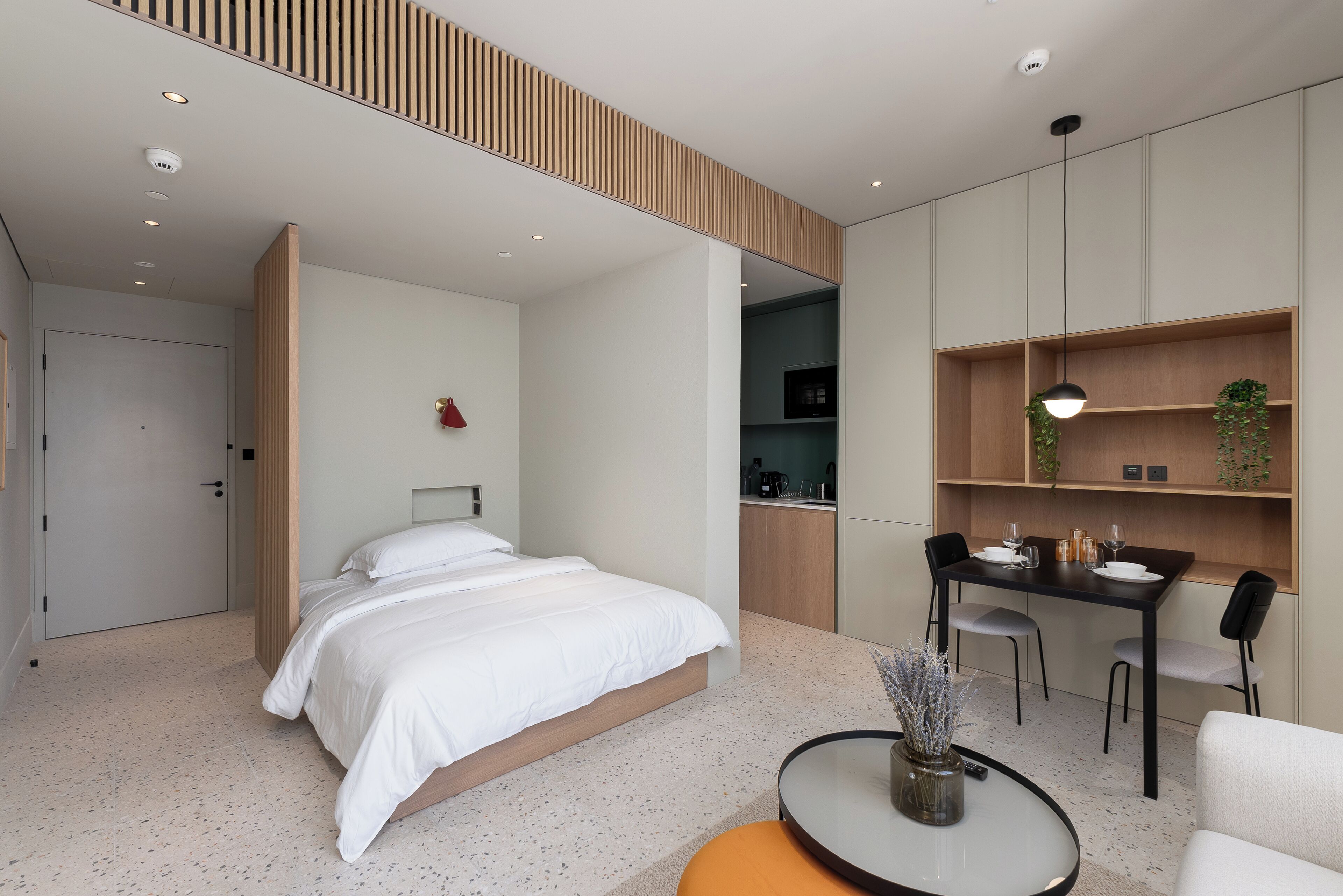 Een moderne hotelkamer met een bed, een zithoek en een kitchenette.