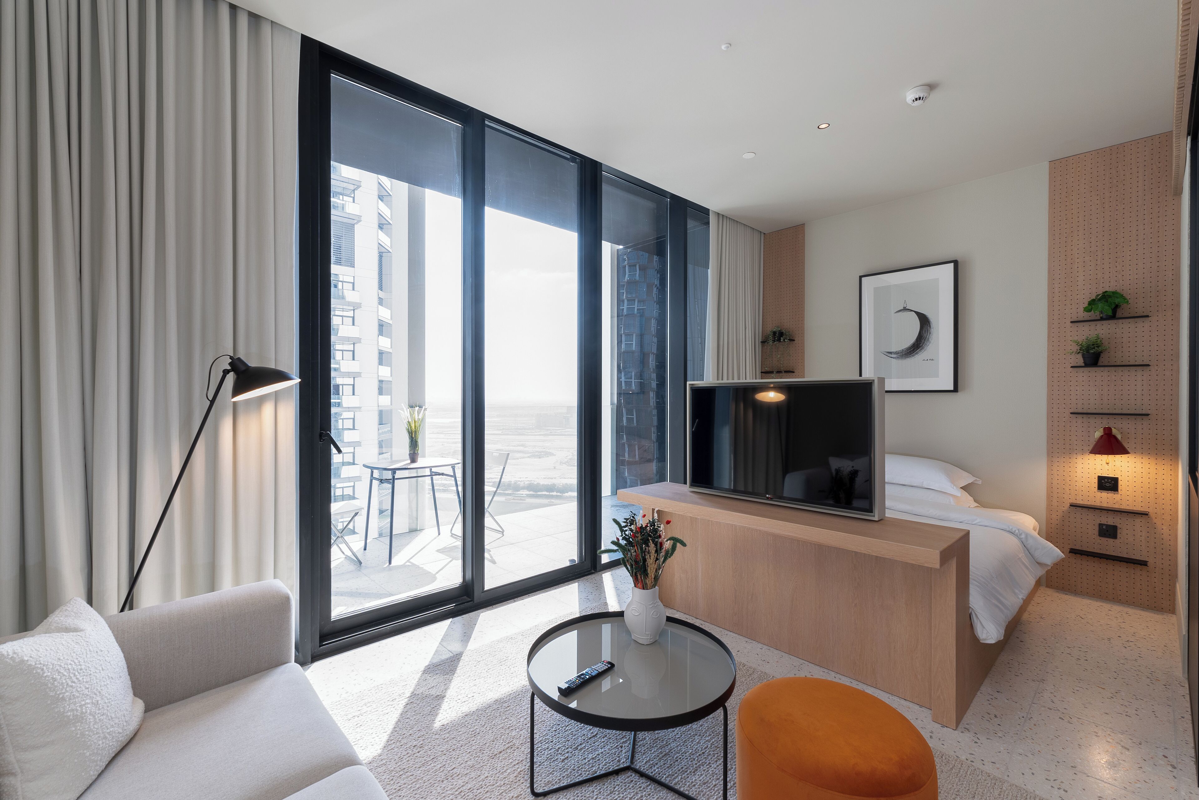 Une chambre d’hôtel moderne dotée d’un grand balcon, d’une télévision, d’un canapé, d’une petite table et d’un lit.