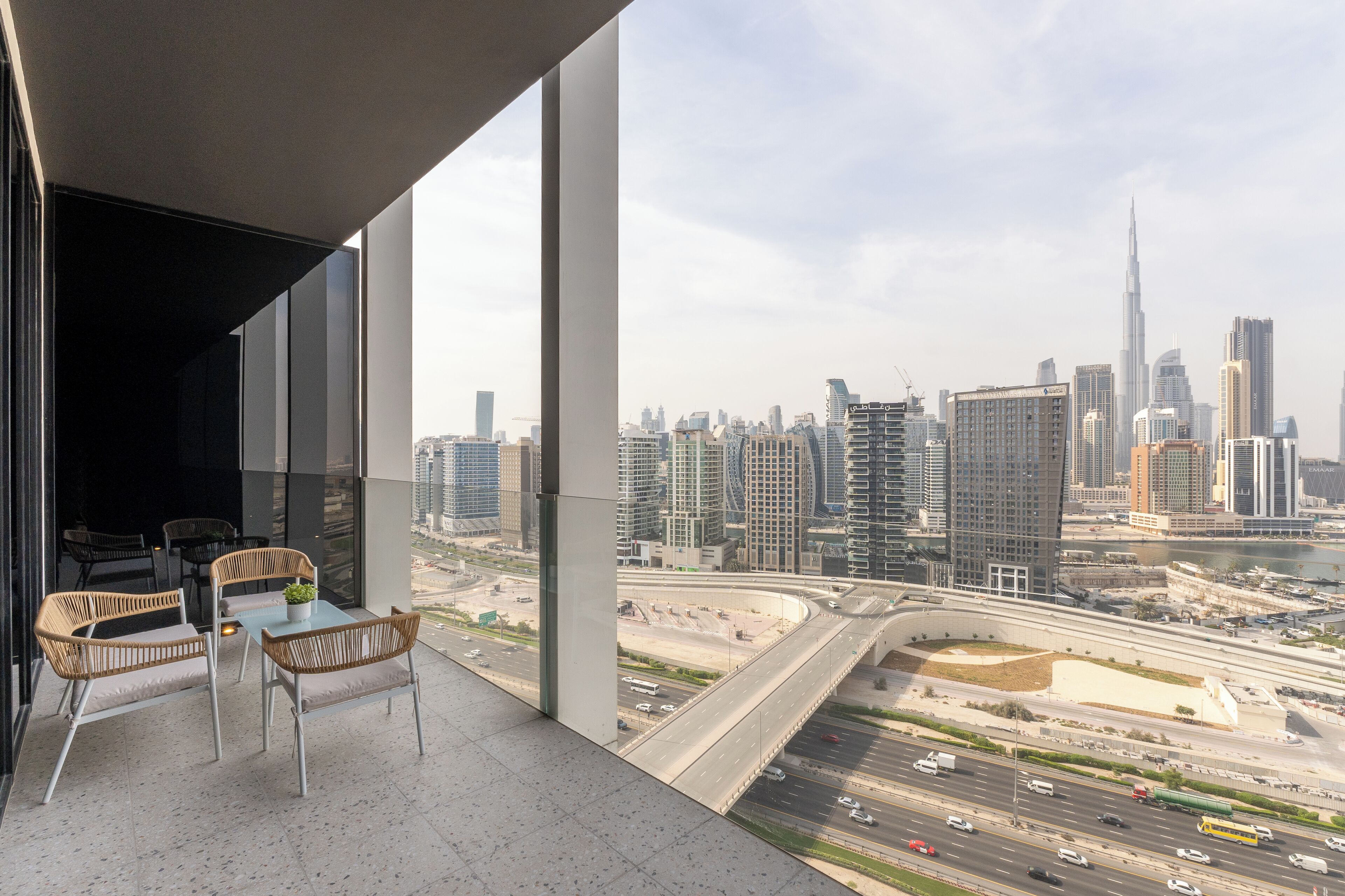 A balcony with wicker furniture and a city view.