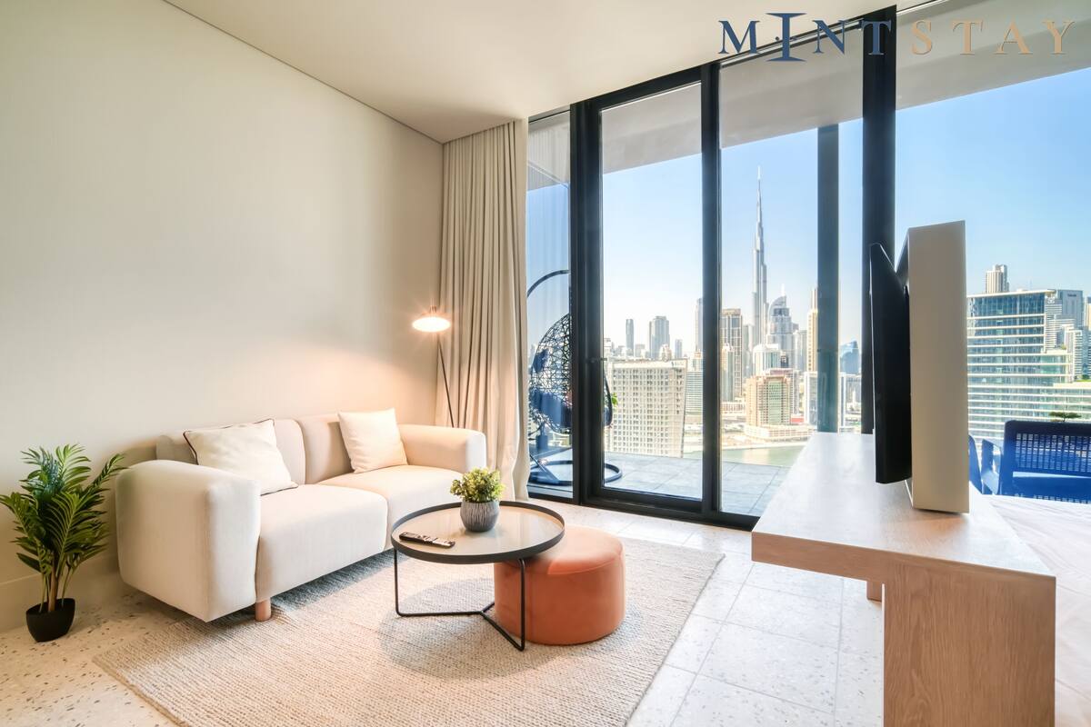 A modern living room with a sofa, a round coffee table, and a TV on a wooden stand.