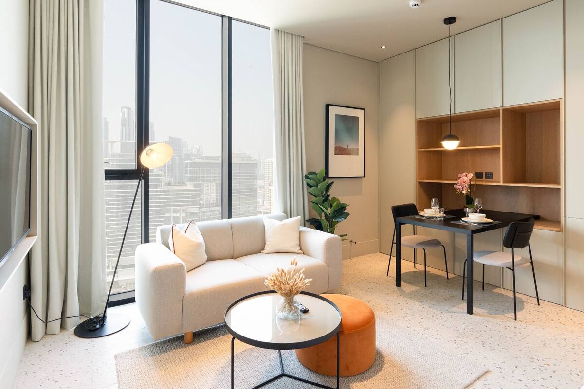 A modern living room with a sofa, a round coffee table, and a dining area with a small table and chairs.