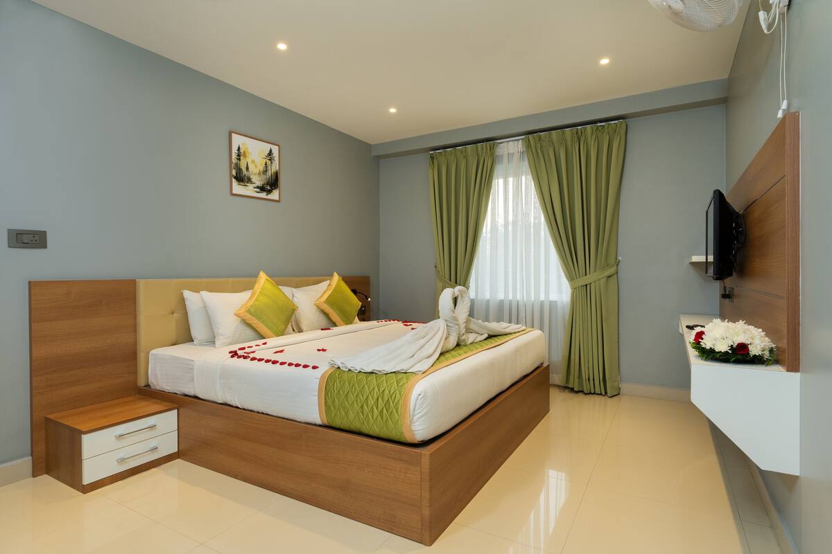 A modern bedroom with a wooden bed, a bedside table, a flat-screen TV, and a wall-mounted TV.