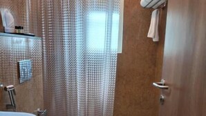 A bathroom with a toilet, a sink, and a shower curtain. - Hotel Grand Alleppey (Ambalapuzha)