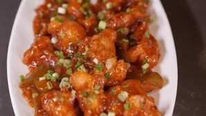 A white rectangular plate with a dish of glazed chicken pieces garnished with green onions. - Hotel Grand Alleppey (Ambalapuzha)