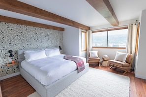 A bedroom with a large bed, a view of the city, and a wooden ceiling. - Romantic Swiss Chalet with Mountain Views (Golden)