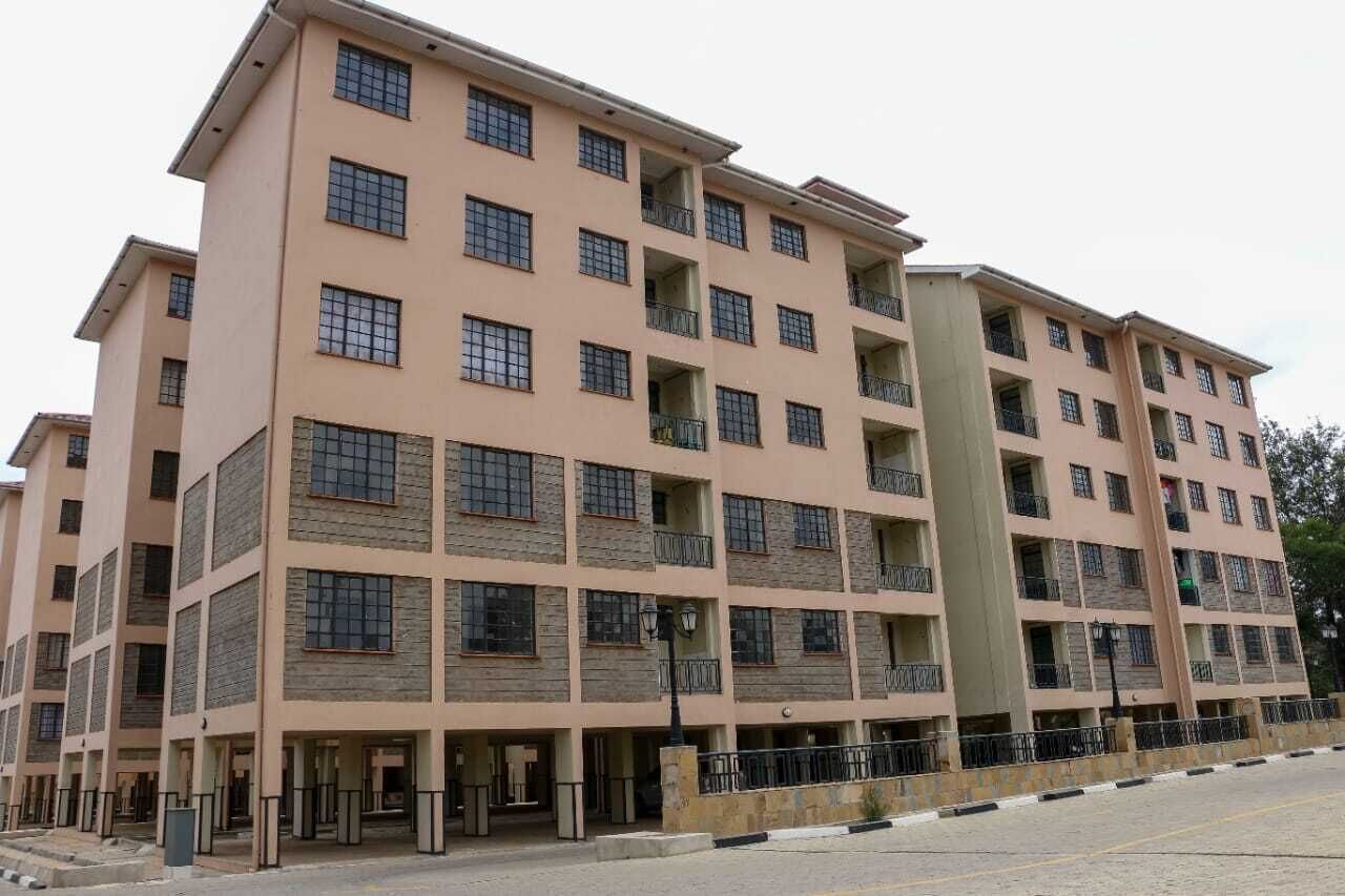 Un edificio residencial de varios pisos con fachada color beige, múltiples balcones y una entrada central.