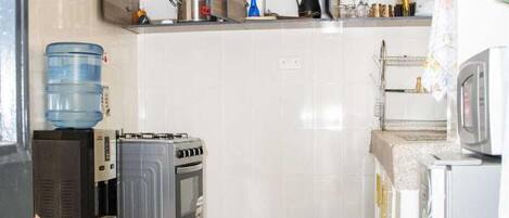 A compact kitchen with a refrigerator, microwave, stove, and water dispenser.