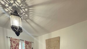 A bedroom with a bed, a nightstand, a lamp, and a window with curtains.