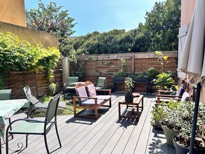 A wooden deck with outdoor furniture, a table, and potted plants.