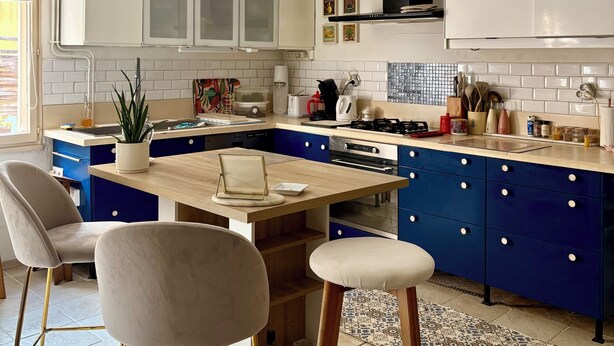 A modern kitchen with a central island, blue cabinets, and a white countertop.