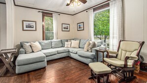 A living room with a sectional sofa, a rocking chair, a wooden coffee table, and a ceiling fan. - 5 BR, 2 BA home in Downtown Ludington, Sleeps 14. (Ludington)