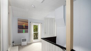 A hallway with a white radiator, a painting of a lighthouse, and a door leading to a balcony. - 5 BR, 2 BA home in Downtown Ludington, Sleeps 14. (Ludington)
