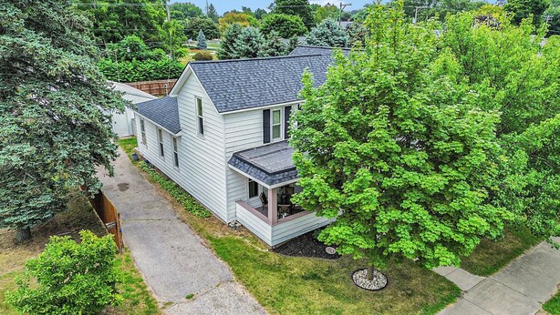 A two-story house with a covered porch and a large tree in front. - 5 BR, 2 BA home in Downtown Ludington, Sleeps 14. (Ludington)