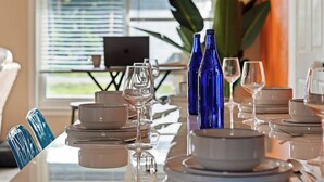 A dining table set with plates, glasses, and blue vases.