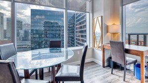 Ein moderner Büroarbeitsplatz mit Glastisch, Ledersesseln, einem Holzbüro und einem großen Fenster mit Blick auf die Stadt.
