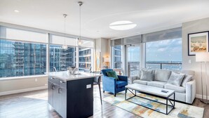 Ein modernes Wohnzimmer mit Kücheninsel, großen Fenstern und Blick auf die Stadt.