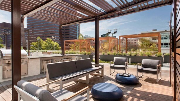An outdoor patio with a wooden pergola, seating area, and a grill. - Luxury Apt Near Charles River with Sky Terrace Access (Cambridge MA)