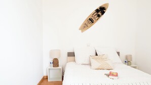 A minimalist bedroom with a bed, bedside tables, and a surfboard decoration.