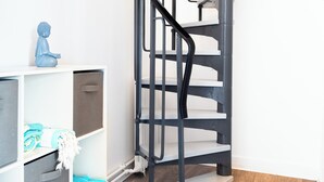 A modern interior with a spiral staircase, wooden flooring, and a white storage unit with a blue decorative item.