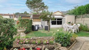 A garden with a patio area, outdoor seating, and a variety of flowers.