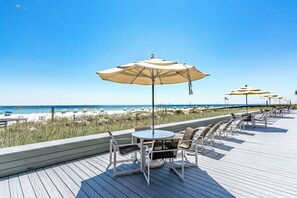 Relax on the beachfront deck with unobstructed ocean views, comfortable seating, and shade from umbrellas.