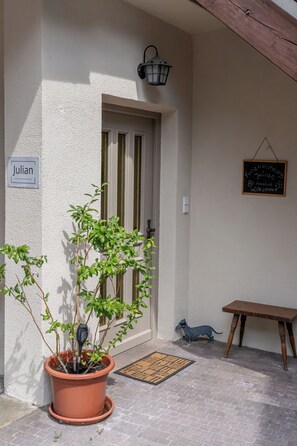 A door with a sign, a potted plant, a small table, and a wall-mounted sign. - Centrally located vacation apartment in Tramin  (Tramin an der Weinstraße)
