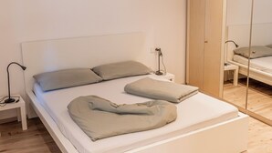 Een moderne slaapkamer met een eenpersoonsbed, nachtkastje, lamp en een garderobe.