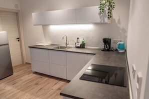 Een moderne keuken met een inbouwoven, een koffiezetapparaat en een waterkoker op het aanrecht.