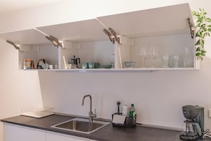 A kitchen with a built-in sink, a coffee maker, and a shelf with glassware. - Centrally located vacation apartment in Tramin  (Tramin an der Weinstraße)