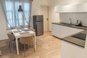 A modern kitchen with a built-in oven, a sink, and a dining area with a table and chairs.