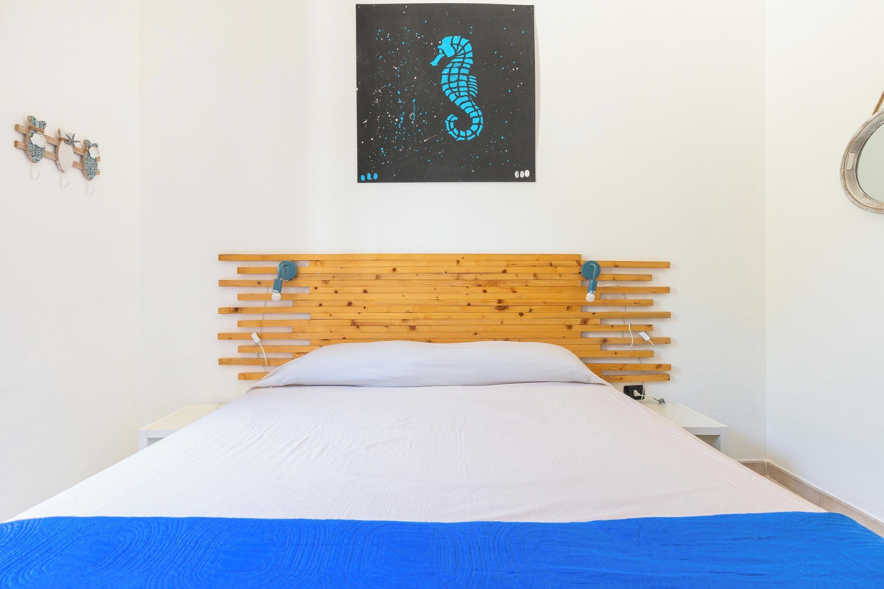 A bed with a wooden headboard, a white pillow, and a blue bedspread.
