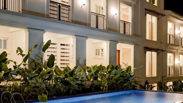 Piscina com borda azulejada, rodeada por vegetação exuberante.