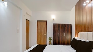 Quarto com cama, guarda-roupa, mesa de cabeceira e luminária na parede.