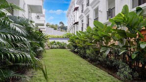 Um pátio com gramado bem cuidado, rodeado por edifícios brancos com varandas e grandes janelas.