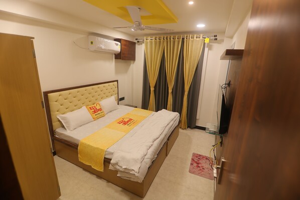 Une chambre d’hôtel équipée d’un lit, d’un ventilateur de plafond, d’un climatiseur et de rideaux.