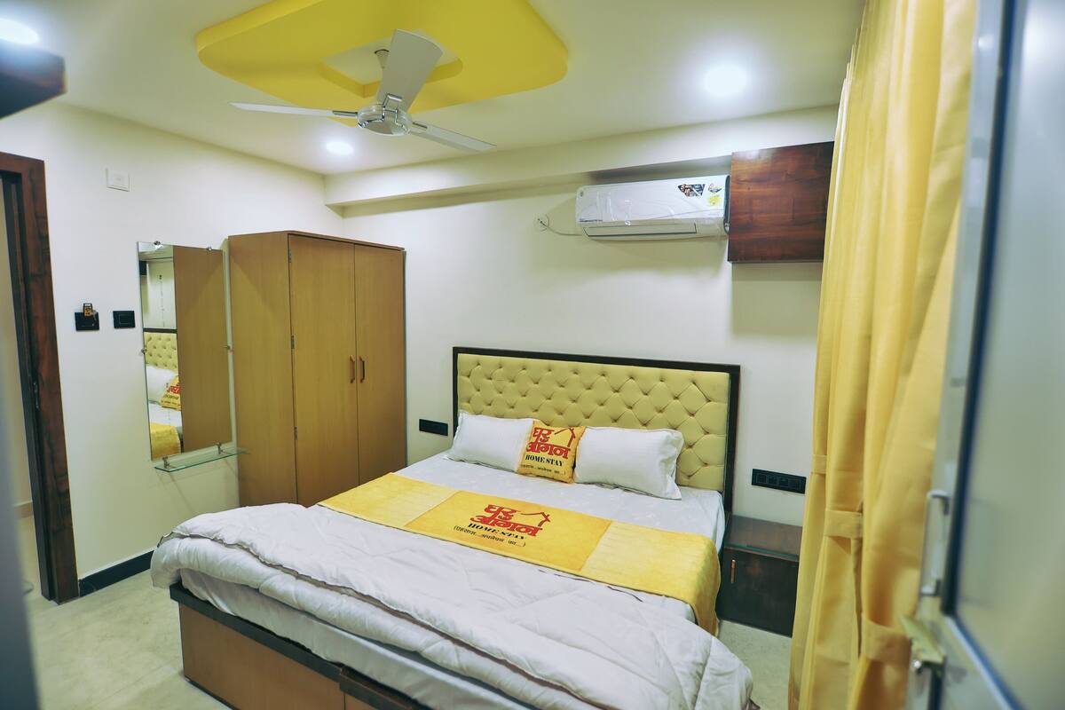 Quarto de hotel com cama, ventoinha no teto, ar condicionado, guarda-roupa e espelho.