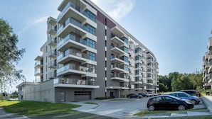 Un immeuble résidentiel à plusieurs étages, doté de balcons, d’un garage et d’un espace de stationnement.