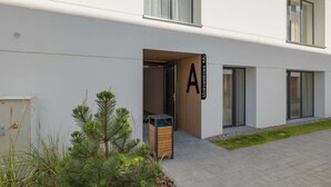 Ein modernes Gebäude mit einem gut sichtbaren Eingang, einem Schild mit der Zimmernummer 4A und einer kleinen Außenbereich-Sitzgelegenheit mit Tisch und Stühlen.