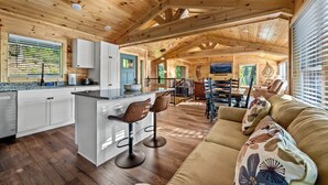 Eine geräumige Holzhütte mit Küche, Essbereich und Wohnzimmer.