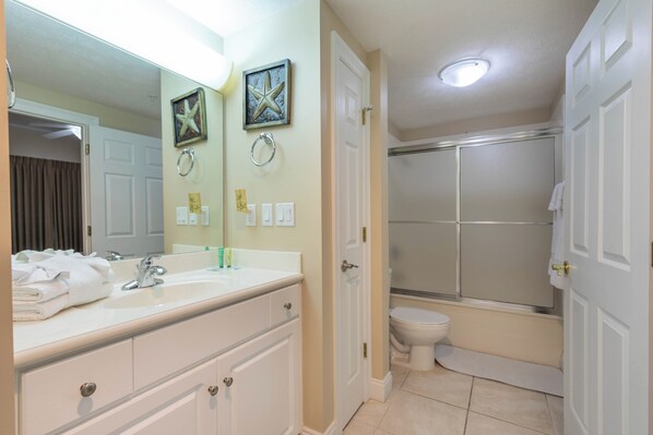 Une salle de bain équipée d’un lavabo, d’un miroir, de toilettes et d’une douche.