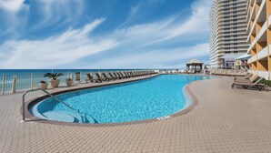 A swimming pool with a curved edge, surrounded by lounge chairs and potted plants.