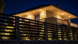 A stone building with a balcony, a wooden fence, and a night sky. - Heraklia villa sea view pool & jacuzzi (XALKIDIKI)