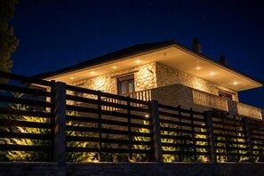 A stone building with a balcony, a wooden fence, and a night sky.