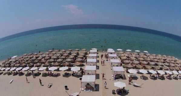A beach with numerous umbrellas and tents, suggesting a resort setting.