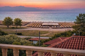 A beachside view with a restaurant, umbrellas, and a mountainous backdrop.